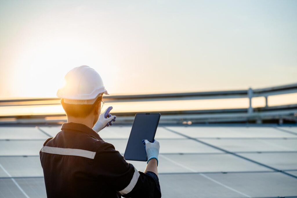 ヘルメットを被った太陽光ぱねるの設置業者が太陽光パネルを設置する画像