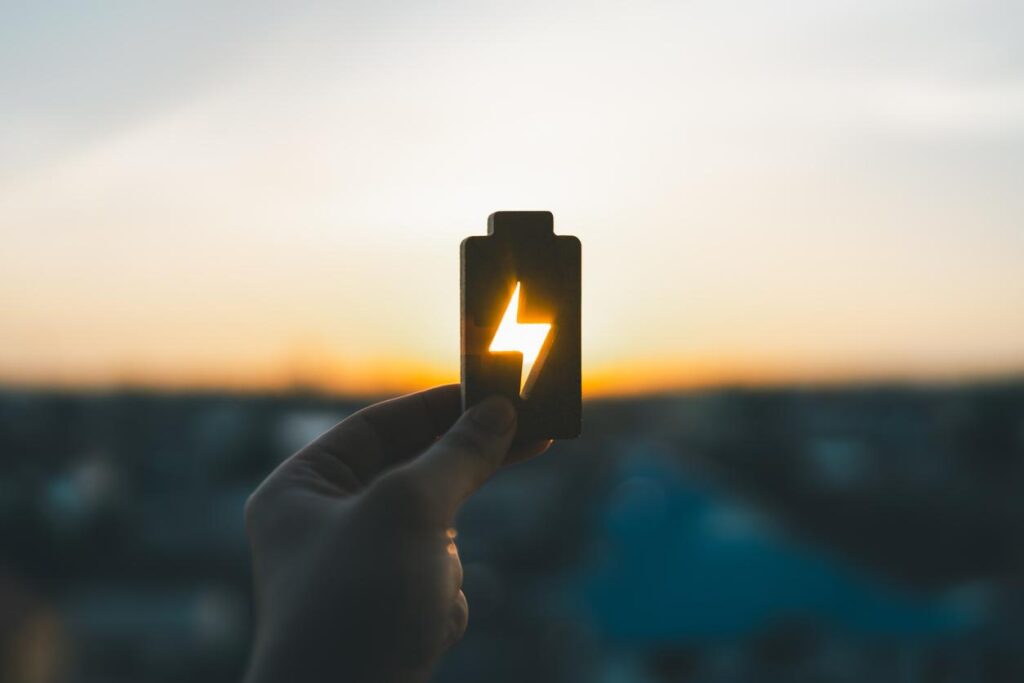 夕日を背景に蓄電池を持つ手の画像