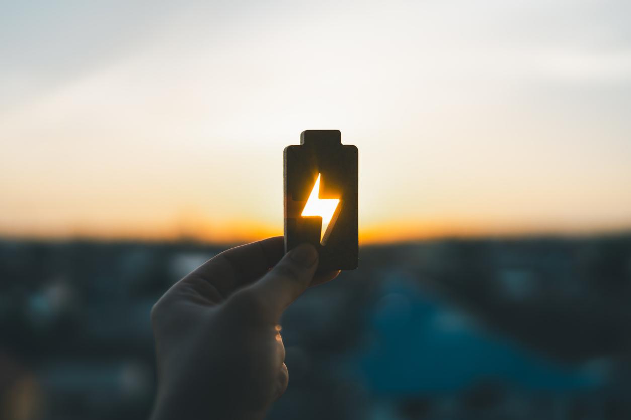 夕日を背景に蓄電池を持つ手の画像
