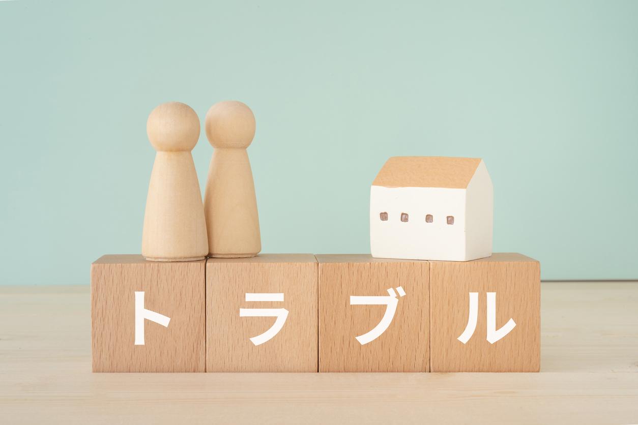 木のブロックが4つ横に並んでいる。ボックスには1文字づつトラブルと書かれている。ボックスの上に人形が2体と家が乗っている。
