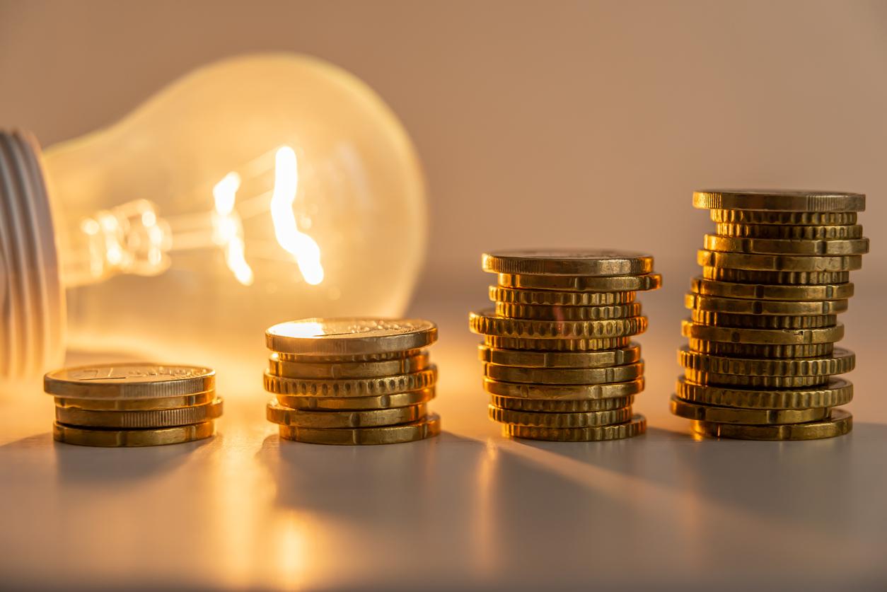 点灯した電球の前に、金貨が段階的に積み重ねられている画像
