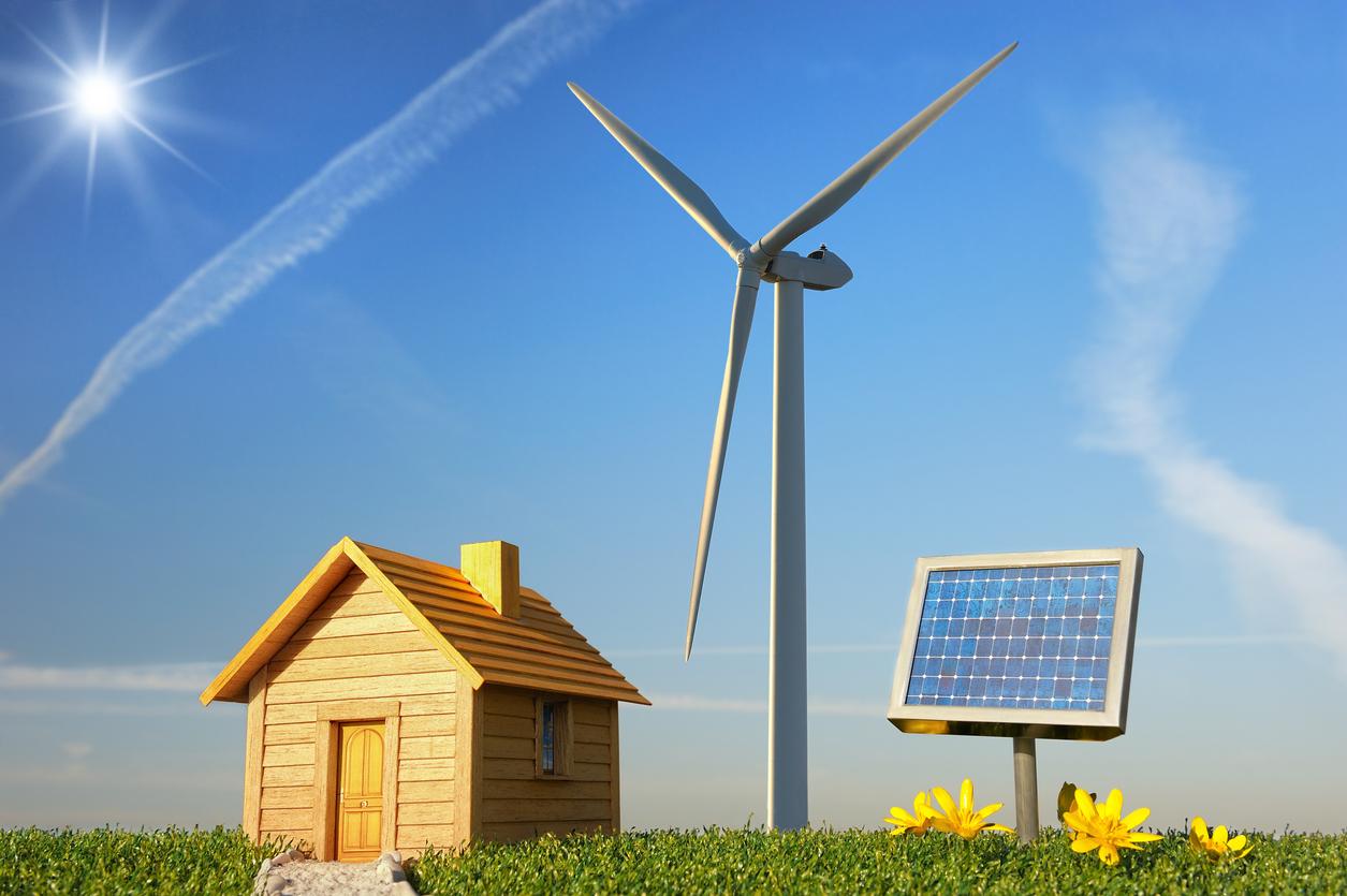 太陽が左上に輝いている晴れた青空の下、風力発電機と太陽光パネルが設置された緑の草地に、木造の小さな家が立っている画像